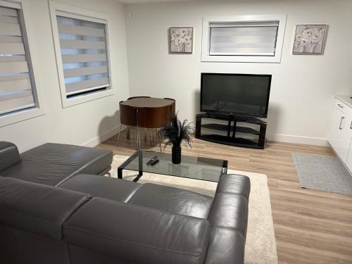 a living room with a leather couch and a television at Calm & Cozy Private Suite in Surrey