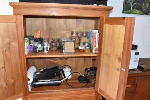 a wooden cabinet with jars of food in it at Te Hoiere Guesthouse in Havelock
