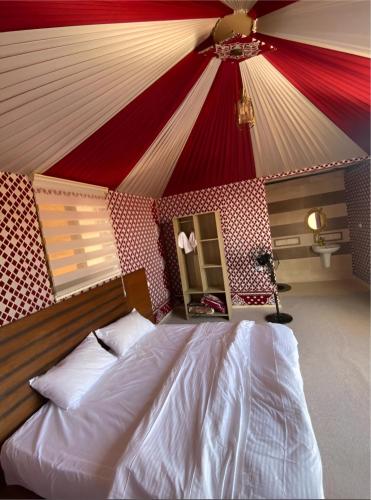 a bedroom with a bed with a red and white ceiling at Rum rose luxury camp in Wadi Rum