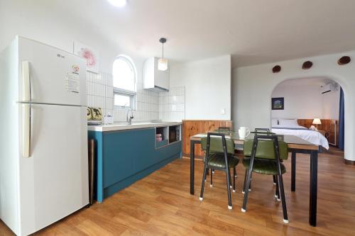 a kitchen with a table and chairs and a refrigerator at Sweet Stay Pension in Seogwipo