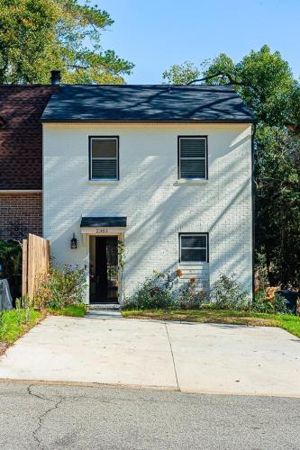 a white house with a driveway in front of it at Elegant Townhome Retreat with King Bed Near I-10, Capitol, FSU & FAMU in Tallahassee