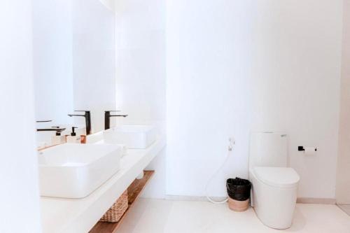 a white bathroom with two sinks and a toilet at 99 Villa Suite - Modern Bedrooms with Dining Area & Enormous Pool in Kerobokan