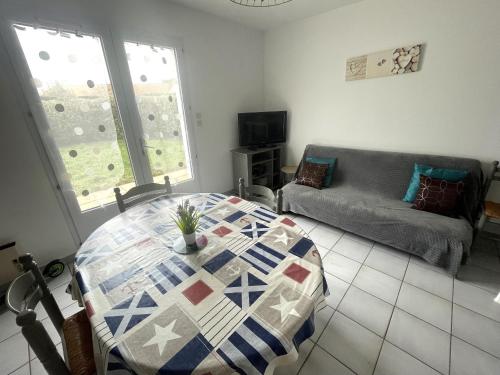 un salon avec une table et un canapé dans l'établissement Maison avec Jardin, 900m Plage, 2 Chambres, Parking Inclus, Animaux Acceptés - La Tranche-sur-Mer - FR-1-22-173, à La Tranche-sur-Mer