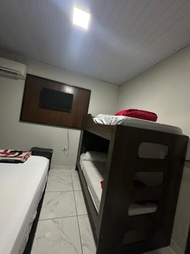 a small room with a bunk bed and a tv at Suite para até 4 pessoas cataratas in Foz do Iguaçu