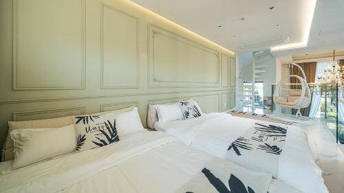 a bedroom with two beds with white sheets at Eudaimonia Poolvilla Jeju 에다모니아 함덕풀빌라 in Jeju
