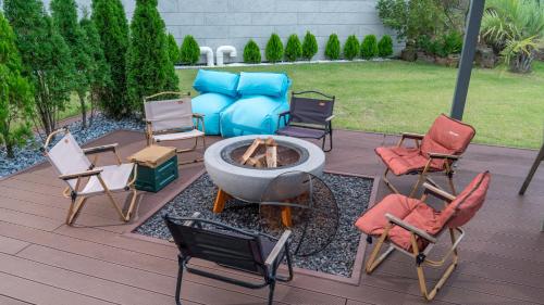 a patio with a fire pit and chairs and a couch at Eudaimonia Poolvilla Jeju 에다모니아 함덕풀빌라 in Jeju