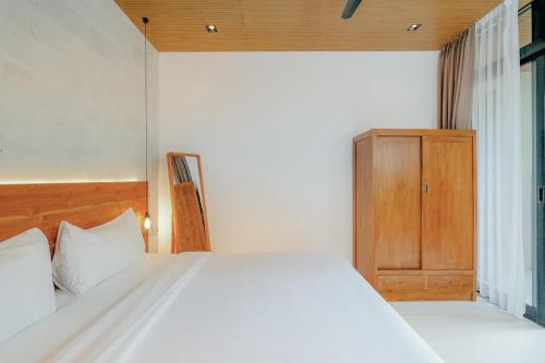 a bedroom with a white bed and a wooden cabinet at 99 Villa Suite - Modern Bedrooms with Dining Area & Enormous Pool in Kerobokan