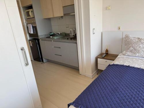 Una pequeña habitación con una cama y una cocina. en RentApartNuevadeLyon12, en Santiago