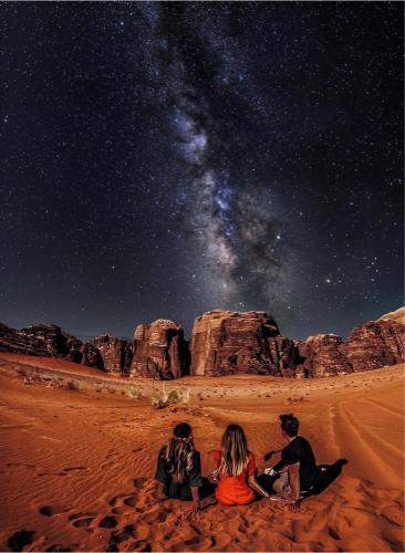 three people sitting in the desert looking at the stars at Rum rose luxury camp in Wadi Rum