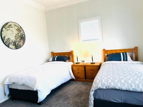 a bedroom with two beds and a clock on the wall at Holiday Home Close to Beach Private Parking in Dunedin