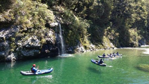a group of people in canoes in a river with a waterfall at Te Hoiere Guesthouse in Havelock