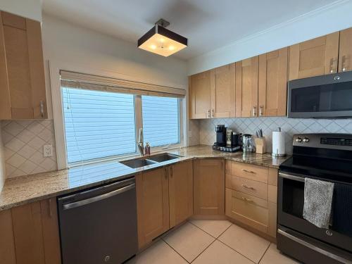 a kitchen with wooden cabinets and a sink and a window at 2Bed Bright & Stylish Ritchie Urban Retreat in Edmonton