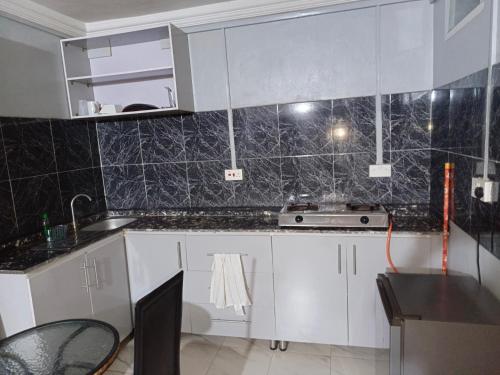 a kitchen with white cabinets and a black tiled wall at Budget one bedroom apartment in Ibadan