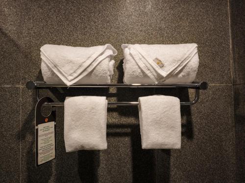 a towel rack in a bathroom with white towels at Azana Garden Hill Resort Blora in Blora
