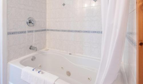 a white bath tub in a white tiled bathroom at Canadas Best Value Inn & Suites Summerside in Summerside