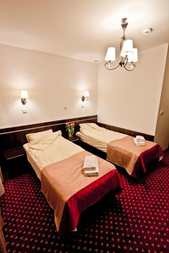 a hotel room with two beds and a chandelier at Hotel Milord in Pułtusk