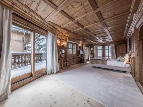 una camera da letto con un letto e una grande finestra di Chalet à Courchevel avec piscine, jacuzzi et vue panoramique - FR-1-613A-13 a Courchevel