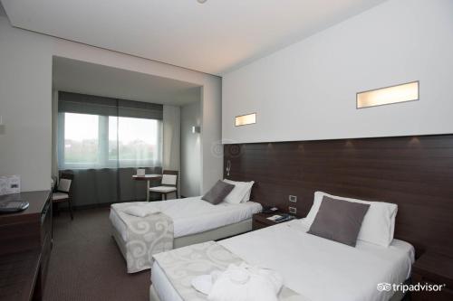 a hotel room with two beds and a table at Hotel Selene Pomezia in Pomezia