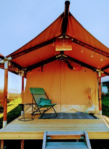une tente avec une chaise sur une terrasse en bois dans l'établissement Yourte ,volcans,randonnées,lacs,quiétude, à Grandeyrolles