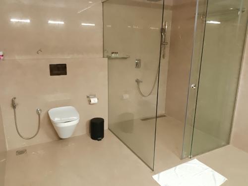 a bathroom with a glass shower and a toilet at UVA Sands Beach Resort in Kundapur