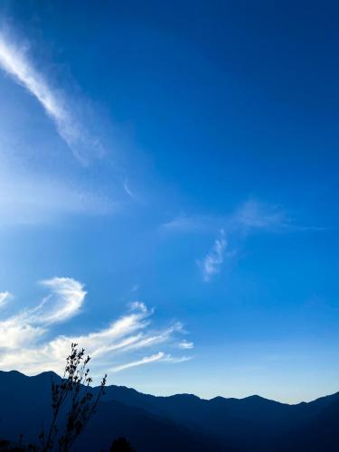 a blue sky with mountains in the background at Aari INN Homestay in Aritar