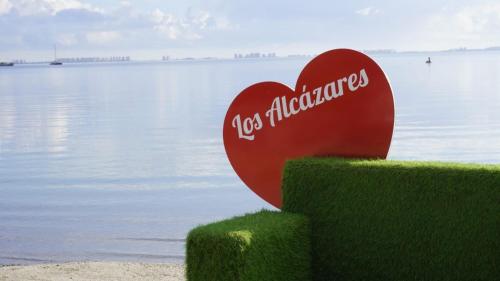 un corazón rojo sentado en la parte superior de la hierba junto al agua en Casa Naranja, en Los Alcázares