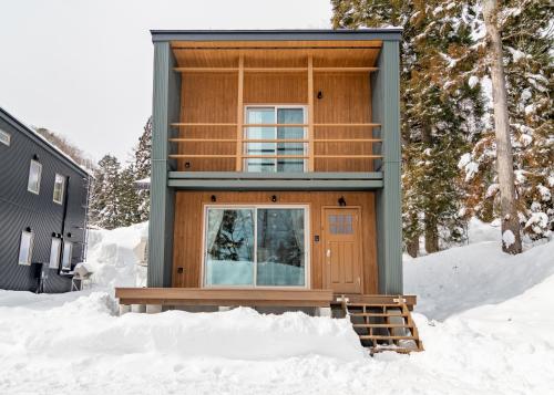 a house in the snow with a balcony at Creekside Chalets Hakuba in Hakuba