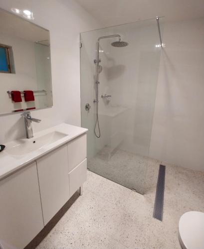 a white bathroom with a shower and a sink at Almond Inn Motel in Tamworth