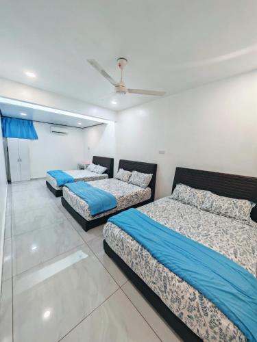 a bedroom with three beds and a ceiling fan at Zzora Home 28 in Alor Setar