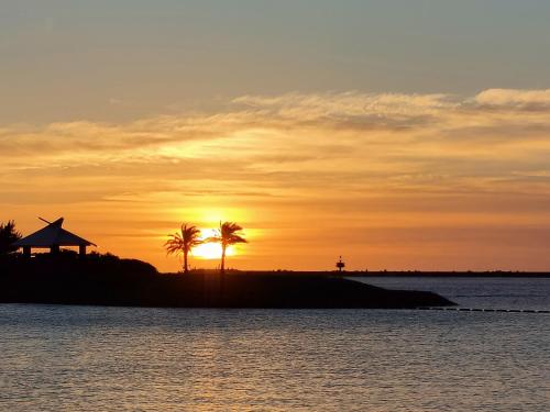 a sunset over a body of water with palm trees at Hotel Torifito Naha Asahibashi in Naha