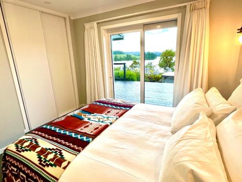 a bed in a room with a window at Luxury Lake House Retreat in Mangakino