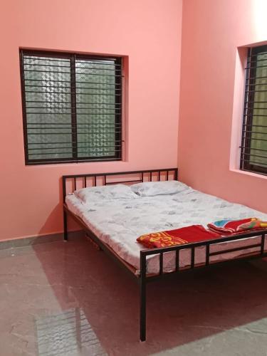 a bed in a room with a pink wall at Bethel Homestay Honnavar in Honāvar