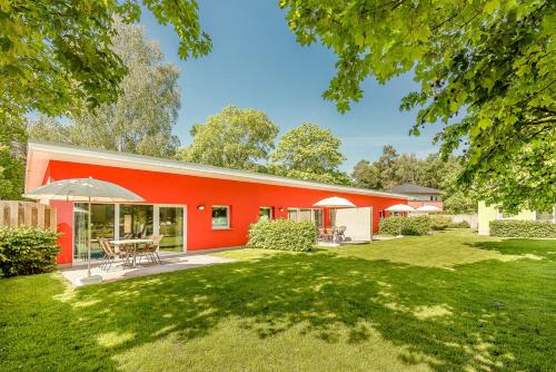 a red house with a patio and a yard at Bungis - 28 Ferienhäuser Am Grimnitzsee G4 in Joachimsthal