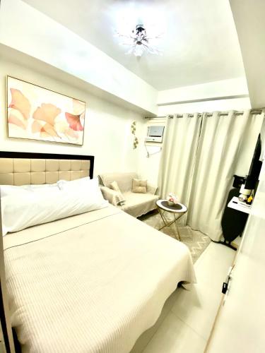 a white bedroom with a bed and a chair at GZ Studio unit- Camella Northpoint in Davao City