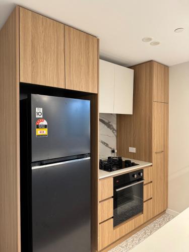 a kitchen with a black refrigerator and wooden cabinets at Two Bedroom, Two Bathroom - Kashmir Apartment in Canberra City in Watson