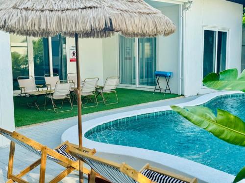 a swimming pool with chairs and an umbrella at Majestic Residence Seaside villa Private beach in Pattaya South