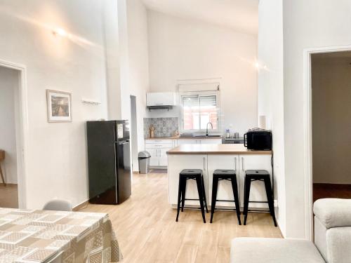 a kitchen with a counter with stools and a refrigerator at Villa des Ajoncs Ermitage les Bains-150m du Lagon in L'Ermitage-Les-Bains