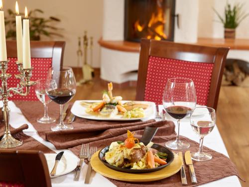 a table with two plates of food and glasses of wine at Hotel Restaurant Zum Schwan in Mettlach