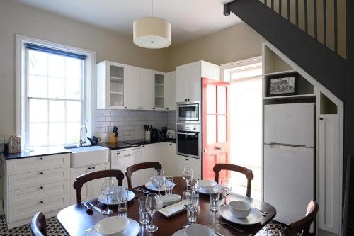 a kitchen with a table and chairs and a kitchen with white cabinets at DeWitt Apartment - 3 Red Doors Battery Point in Hobart