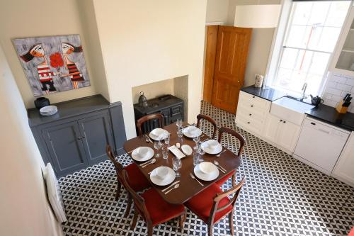 a kitchen with a wooden table with chairs and a kitchen with a tableablish at DeWitt Apartment - 3 Red Doors Battery Point in Hobart