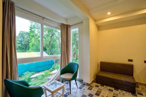 a room with a window and two chairs and a couch at Goa Courtyard by the porto Arpora in Baga