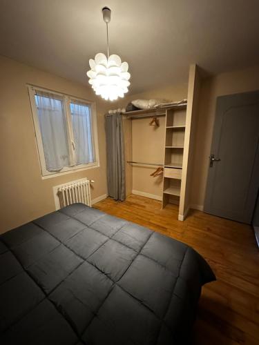 une chambre avec un grand lit et un lustre dans l'établissement Charmante maison de ville, à Margny-lès-Compiègne