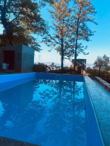 a blue swimming pool with trees in the background at Dwarka By Nature Sweet Homes in Panchgani