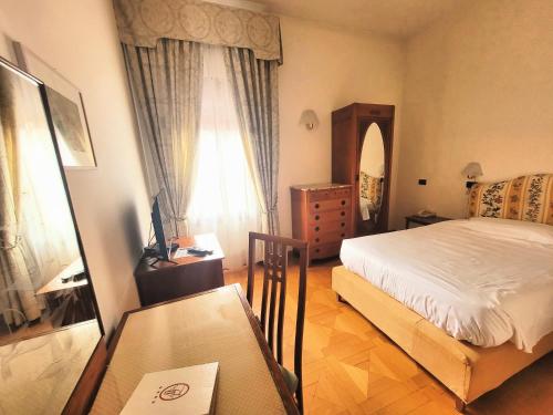 a bedroom with a bed and a dresser and a mirror at Alla Rocca Hotel Conference & Restaurant in Bazzano