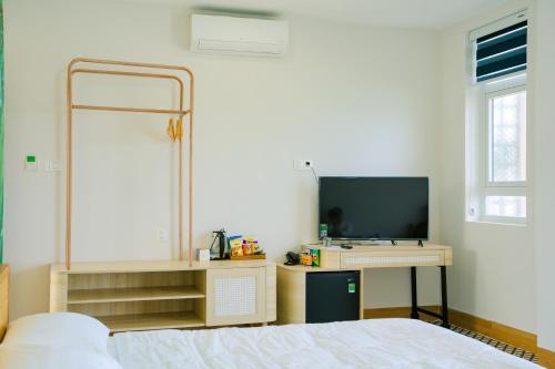 Vĩnh Cửu AnにあるKennal Homeのベッドとテレビ付きの机のある寝室