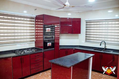 a kitchen with red cabinets and a black counter top at Whispering Hearts Guest House in Bortianor
