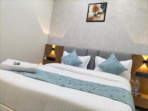 a bedroom with a large white bed with blue pillows at Hotel Paris Plaza in Ahmedabad