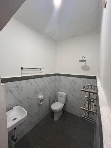 une salle de bain blanche avec toilettes et lavabo dans l'établissement Astika Asri Homestay, à Dalung