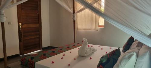 a bed with a white animal on it in a room at Diana Place in Paje