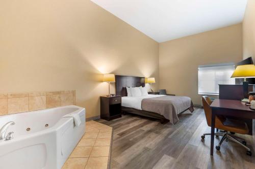 a hotel room with a bed and a bath tub at Quality Inn and Suites Groesbeck in Groesbeck